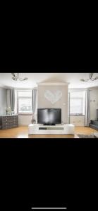 a living room with a television and two windows at Beautiful Views Welsh Valley home in Mountain Ash