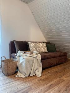 a living room with a brown couch and a basket at Pine & Oak Holiday Home in Fužine