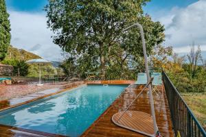 una piscina con una terraza de madera y una valla de metal en Rectoría de Castellar, en La Vall de Bianya