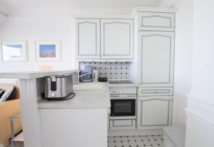 a kitchen with white cabinets and a coffee maker on a counter at Windeby 6D in Wenningstedt