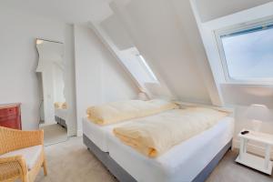 a white room with a bed and a window at Windeby 6D in Wenningstedt