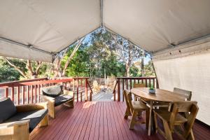 a wooden deck with a table and chairs in a tent at Scamander Sanctuary Holiday Park in Scamander