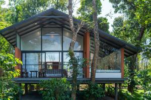 une maison dans les bois entourée d'une terrasse couverte dans l'établissement Crystal Kuruva Nature Resort & Spa, à Wayanad