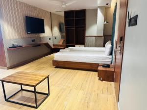 um quarto com uma cama, uma mesa e uma televisão em V HOTEL em Brahmapur