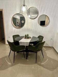 una sala da pranzo con tavolo, sedie e specchi di Little John Luxury Apartment a Pireo