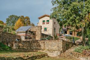 una antigua casa de piedra con una pared de piedra en Rectoría de Castellar, en La Vall de Bianya