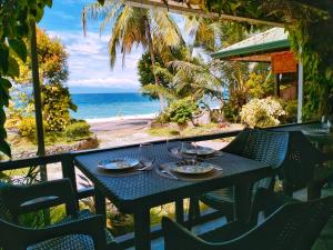 a table with plates of food on a balcony with the beach at Molinillo Vacation Cabin in Ginatilan