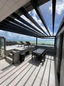 d'une terrasse avec une table et des bancs donnant sur l'océan. dans l'établissement Loft Luxo intermares vista mar, à Cabedelo