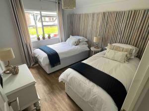 two beds in a small room with a window at Waterside Lodge, Weybourne, Holt in Weybourne