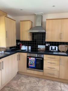 eine Küche mit Holzschränken und einem Herd mit Backofen in der Unterkunft Old Canal-Side Cottage Taff Trail Merthyr Tydfil in Abercanaid