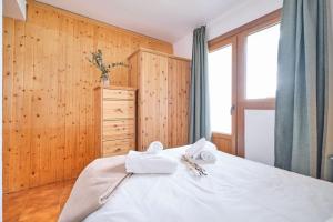 a bedroom with a white bed and a wooden wall at Rincón de Anayet Entrada Autónoma Formigal in Formigal