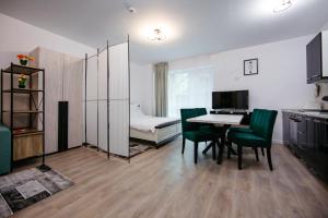 a living room with a table and green chairs at L&V Family Studio in Sinaia