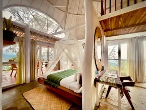 ein Schlafzimmer mit einem Himmelbett in einem Zimmer mit Fenstern in der Unterkunft Manulalu Jungle in Bajawa