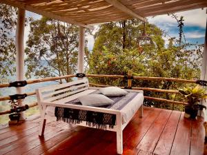 - un lit sur une terrasse couverte avec une terrasse en bois dans l'établissement Manulalu Jungle, à Bajawa