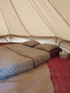 a bed in a tent with a red rug at La Pause Mafate in La Possession