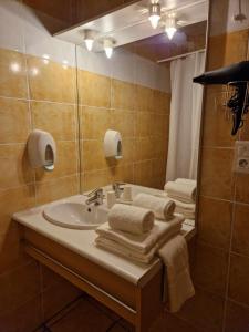 W łazience znajduje się umywalka, lustro i ręczniki. w obiekcie Tempo Hôtel w mieście Millau