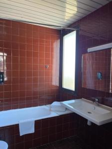 a red tiled bathroom with a tub and a sink at Hotel Bruc in El Bruc