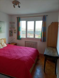 a bedroom with a red bed and a window at Charmant 3 pièces 10 min de Lyon in Villeurbanne