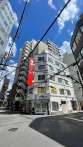 a tall white building with a red sign on it at 幸・3 in Osaka