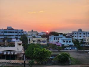 a city skyline with the sun setting behind buildings at Hotel Hariram Tower,Wardha in Wardha