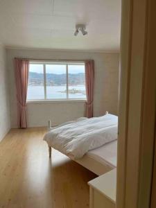 1 dormitorio con cama y ventana grande en Feriehus på Sørlandsøy, en Flekkefjord