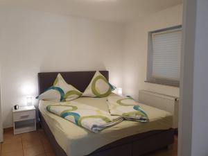 Schlafzimmer mit einem Bett mit gelben und blauen Kissen in der Unterkunft Ferienwohnung Ela 1 in Andernach