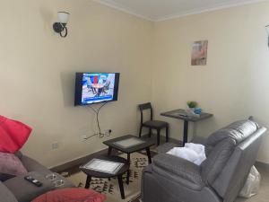 a living room with a couch and a tv on the wall at Lux Suites Narok Holiday Homes in Narok