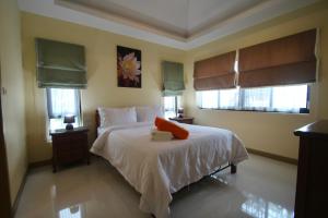 a bedroom with a bed with white sheets and windows at Talay Sawan Pool Villa 27-12 in Bang Sare