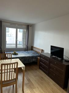 - une chambre avec un lit, une télévision et une table dans l'établissement Appartement Créteil proche Métro, à Créteil