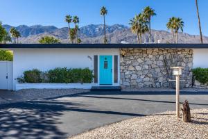 a building with a blue door and palm trees at Chi Chi House in Palm Springs