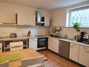 cocina con armarios blancos y mesa de madera en Ferienwohnung Ela 1, en Andernach