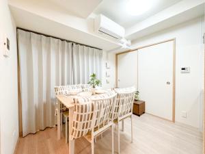 a dining room with white walls and a table and chairs at Apartment Hotel Side of Shinsaibashi Shopping street in Osaka
