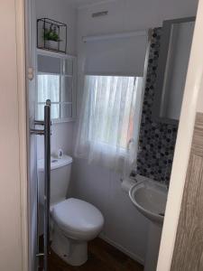 a white bathroom with a toilet and a sink at Haven Caravan Park Cala Gran in Fleetwood +7 photos