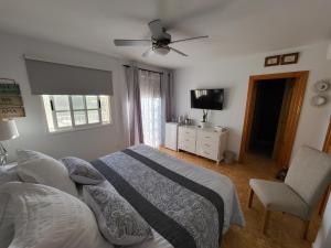 a bedroom with a bed and a tv and a chair at Casa Mariposa Guesthouse in Playa de San Juan