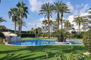 una piscina con palmeras y un edificio en AT119 Nova Torredembarra, en Torredembarra