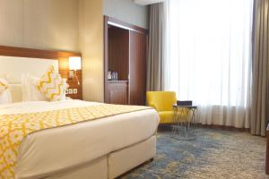 um quarto de hotel com uma cama grande e uma cadeira amarela em Taj Al Worood Hotel em Jeddah