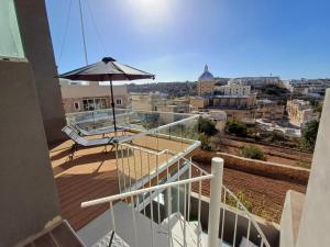 a balcony with an umbrella and a view of a city at Is- Sienja in Kalkara