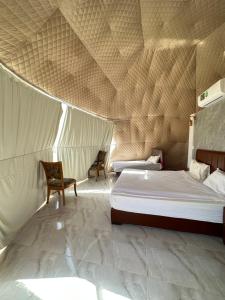 a bedroom with a bed and two chairs in a tent at Wadi rum camp in Wadi Rum
