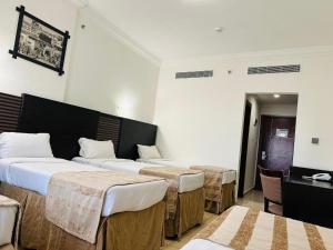 a hotel room with three beds and a desk at Jawharet Al Majd Hotel in Makkah