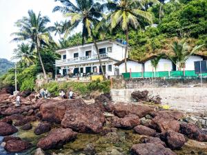 亞蘭博的住宿－Shree Sai Beach Stay，棕榈树岩石岸边的房子