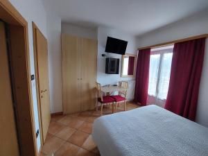 1 dormitorio con 1 cama y 1 mesa con silla en Bed & breakfast Villa Maria en Cavalese