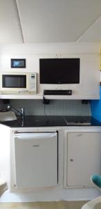 uma cozinha com 2 frigoríficos, um micro-ondas e uma televisão em Barco 45 pés - 12 pessoas em Tamandaré