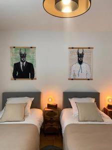 2 Betten in einem Zimmer mit 2 Bildern eines Mannes im Anzug in der Unterkunft Les Lauriers Blancs, villa avec piscine in LʼIsle-sur-la-Sorgue
