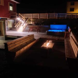 un patio por la noche con una hoguera y un sofá en New flat with hot tub - No3 en Oyndarfjørður