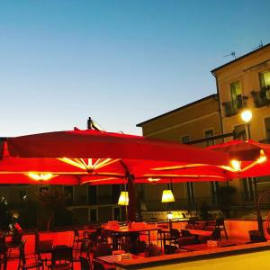 un restaurante con sombrillas rojas, mesas y sillas en Casa di Nenna, en Vallo della Lucania