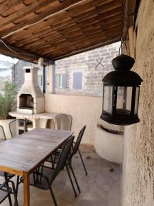 une table et des chaises dans une terrasse avec une lampe dans l'établissement Typique maison de village, à Saint-Quentin-la-Poterie