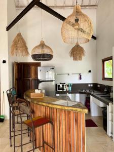 a kitchen with a bar with chairs and pendant lights at Villa Tom & Lucie Bingin Beach in Uluwatu