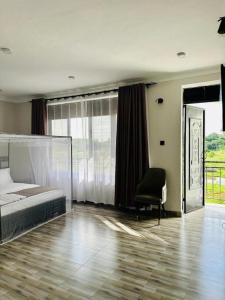 1 dormitorio con 1 cama y 1 silla en el suelo de madera en Kacoke Madit Hotel and Cultural Centre, Gulu en Gulu