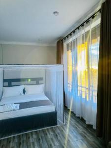 a bedroom with a canopy bed and a window at Kacoke Madit Hotel and Cultural Centre, Gulu in Gulu