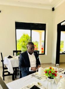un hombre de traje sentado en una mesa en Kacoke Madit Hotel and Cultural Centre, Gulu en Gulu